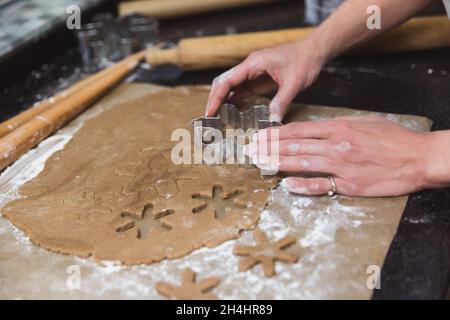 Femme fait des biscuits de pain d'épice de noël sur fond noir et rouge.Cadeau de Noël, pain d'épice maison.Mains, gros plan Banque D'Images