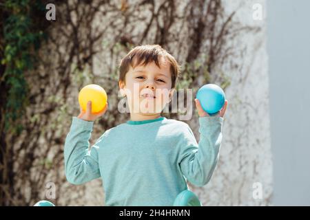 Enfant avec des boules de plastique colorées dans ses mains. Banque D'Images