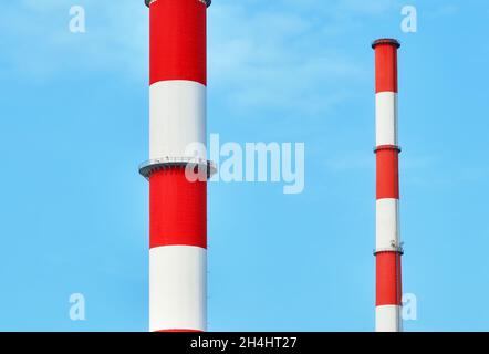 Gros plan des cheminées peintes en rouge et blanc contre le ciel bleu. Banque D'Images