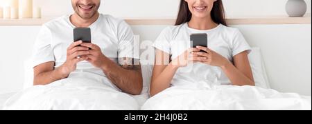 Court souriant caucasien jeune homme et femme tapant sur des smartphones, bavarder en ligne et surfer sur Internet Banque D'Images