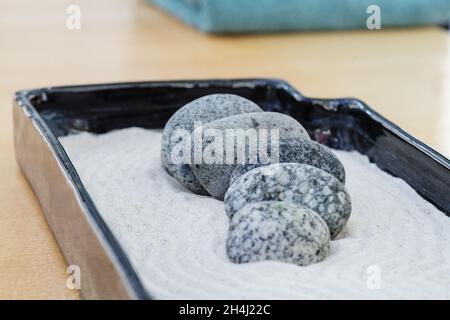 petite décoration zen avec sable et pierres de granit qui calme et sont échelonnés.À l'arrière-plan une serviette vert lime Banque D'Images