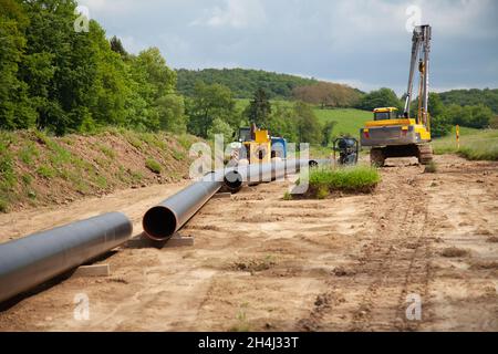 Tuyau de gaz débranché dans le côté de la campagne en diagonale à partir de la gauche en diagonale par photo avec des machines de pose de gaz en arrière-plan Banque D'Images