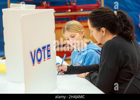 Buckingham, États-Unis.02 novembre 2021.De gauche à droite, Allyson McNair, 10 ans, et sa mère Jill McNair, de Buckingham, s'assoient à une table pendant que Jill dépose son bulletin de vote au bureau de vote local le mardi 02 novembre 2021 à la Central Bucks East High School, à Buckingham, en Pennsylvanie.( Credit: William Thomas Cain/Alamy Live News Banque D'Images