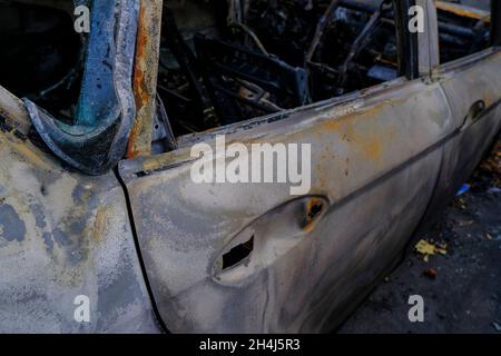 Porte de voiture brûlée dans la rue en gros plan.Émeute, protestation civile, hooliganisme, criminel dans la ville. Banque D'Images