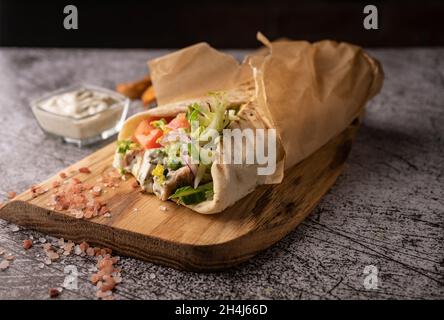 doner kebab, un shawarma dans une fosse de légumes frais et de viande. avec de grandes épices. service de restaurant. sur fond sombre. pour les menus et les annonces Banque D'Images