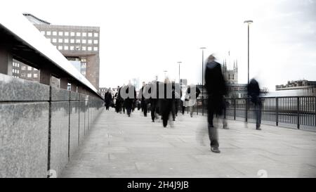 Flou commercial.Vue abstraite créative du trafic piétonnier traversant le London Bridge pendant les heures de pointe matinales. Banque D'Images