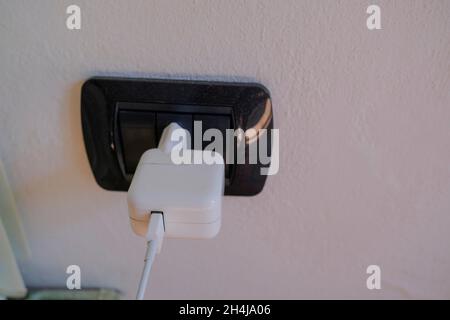 Chargeur blanc sur fiche électrique noire sur un gros plan mural.Chargement du smartphone.Technologies Banque D'Images