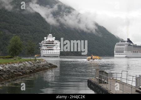 Deux navires de croisière sont amarrés dans un fjord en Norvège et attendent que les passagers débarquent avec des dinghies Banque D'Images