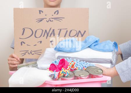 Une femme donne main don pour soutenir un abri pour animaux.Les bénévoles collectent de la nourriture et des fournitures pour animaux de compagnie, préparant des articles donnés dans des boîtes pour animaux Banque D'Images