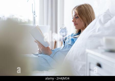 jeune femme gaie lisant un livre dans la chambre Banque D'Images