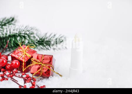 Un tube de baume à lèvres incolore pour protéger et nourrir les lèvres.Cosmétiques d'hiver.Maquette de conteneur à proximité avec cadeaux et brindilles de sapin en toile de fond.CHRI Banque D'Images