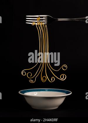 Fourchette avec des brins conceptuels de spaghetti suspendus sur un bol Banque D'Images
