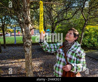 Hidden Garden, Glasgow, Écosse, Royaume-Uni, 03 novembre 2021.COP26: ORIGINS, un festival d'art et de culture autochtone d'une année.Photo : Ann-Marie, bénévole dans les jardins, regarde un des messages sur le changement climatique accrochés à un arbre Banque D'Images