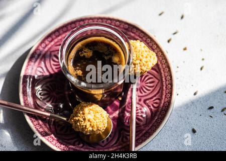 Boules de bonbons maison enrobées de noix hachées avec une tasse de café noir Banque D'Images