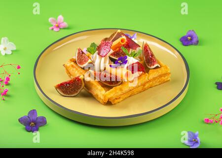 Gaufres belges avec figues crème, fleurs et baies Banque D'Images