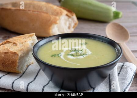 Soupe de purée de courge végétale.Une courgette entière, des tranches de pain et une cuillère en bois sur fond de bois.Vue latérale. Banque D'Images