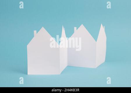 Rangée de maisons en papier blanc sur fond bleu, espace de copie vide, immobilier symbole Banque D'Images