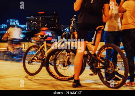 Résumé groupe de cyclistes dans les rues de la ville la nuit, pieds de gros plan, roues, bicyclettes.Concept de sport, style de vie sain moderne, arrière-plan flou Banque D'Images