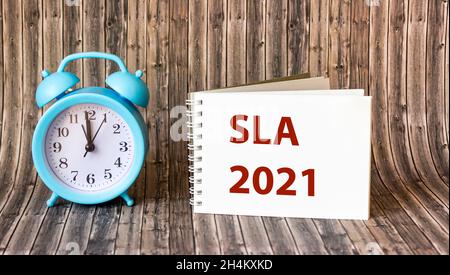 Contrat de niveau de service SLA 2021 - mot sur le bloc-notes et arrière-plan en bois.Concept commercial et financier Banque D'Images