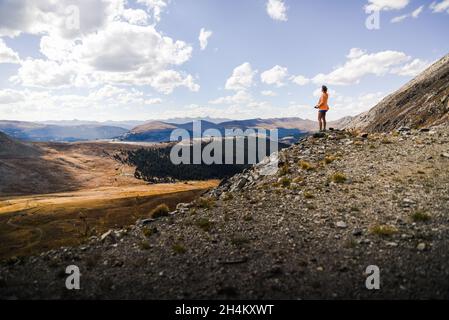 Une femme debout au sommet d'une montagne qui donne sur un pré Banque D'Images