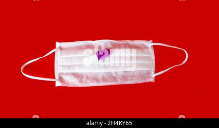 Une nouvelle maladie causée par le coronavirus, nommé 2019-nCoV.Sur fond rouge se trouve un masque avec une pilule du virus Banque D'Images