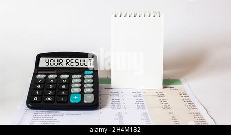 Le mot votre résultat, écrit sur la calculatrice, s'affiche sur les documents avec des calculs et un fond blanc.Bloc-notes pour l'écriture Banque D'Images