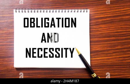 ENGAGEMENT ET NÉCESSITÉ, le texte est écrit sur un bloc-notes, sur fond marron. Banque D'Images