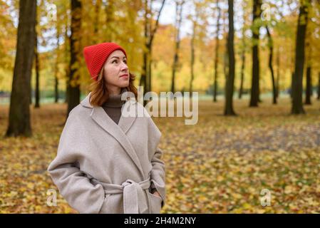 Portrait d'une femme en manteau de laine et chapeau rouge au parc d'automne Banque D'Images