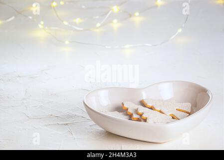 Arbres de noël en pain d'épice dans un bol blanc de foi en forme de coeur sur une surface en béton, vue rapprochée.Concept de fête de Noël avec spac Banque D'Images