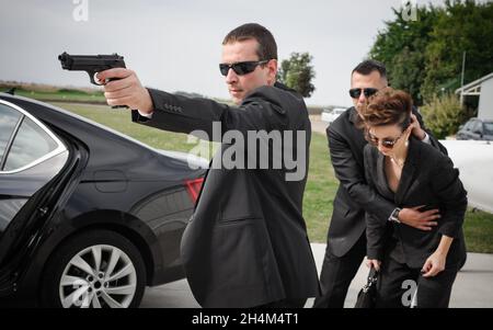 Une équipe armée professionnelle de gardes du corps féminins et masculins protège la personne célébrité en limousine de voiture.BodyGuard et protection de sécurité VIP.Profess Banque D'Images