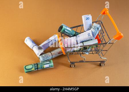 Billets en dollars et en euros dans le panier.Le shopping et le consumérisme. Banque D'Images