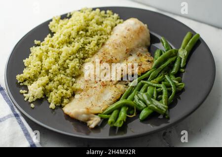 Poisson merlu, haricots verts et couscous dans l'assiette Banque D'Images