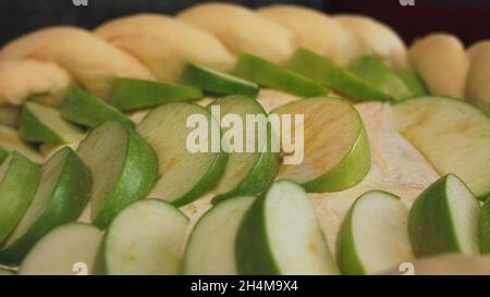 Préparation d'une Charlotte de pomme à la maison, vue rapprochée.Morceaux de pomme verte coupés frais de la pâte brute dans une forme de queue de cochon, concept de coo Banque D'Images