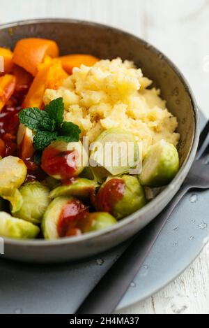 Plat maison avec courge d'hiver, choux de Bruxelles, purée de pommes de terre et sauce douce et épicée. Banque D'Images