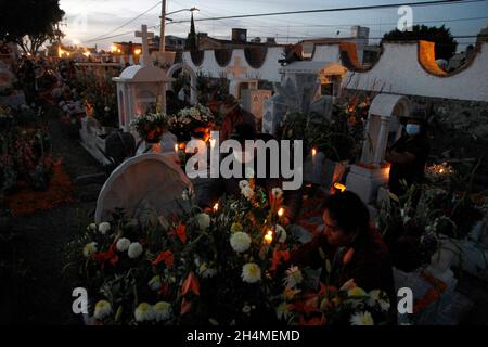 Les membres de la famille décorent et éclairent les tombes de leurs proches qui se reposent dans le cimetière mixte de San Andrés.Une tradition culturelle qui revient après avoir été suspendue pendant un an en raison de la pandémie de Covid19 dans la ville de San Andrés Mixquic.Le 2 novembre 2021 à Mexico, Mexique.(Photo de Luis Barron/Eyepix Group) Banque D'Images