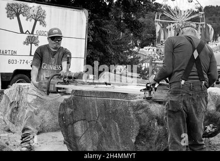 Deux hommes utilisent une scie à main pour couper des bûches en blanc à Deerfield Fair - Deerfield, New Hampshire.Film noir et blanc Ilford XP2. Banque D'Images