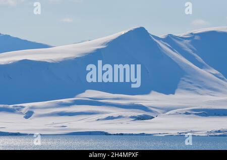 La beauté magique de Svalbard.Neige exceptionnellement bleue contre le ciel dégagé.Fjords et montagnes avec neige éternelle sur l'île de Svalbard Banque D'Images