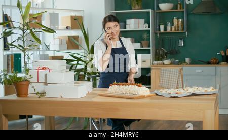 Une femme d'affaires prospère gérant ses travaux d'affaires dans une cuisine confortable Banque D'Images