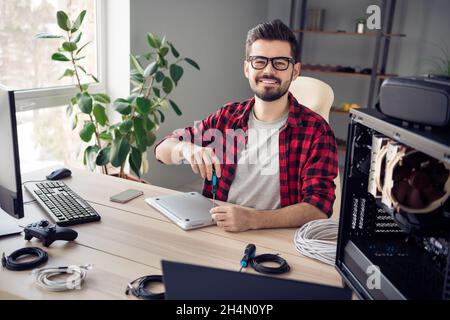 Portrait d'un sympathique homme tendance et expérimenté qui répare l'appareil processus de réussite de carrière au poste de travail de bureau à l'intérieur Banque D'Images