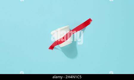 gobelet en carton blanc collé avec du ruban adhésif rouge sur le fond bleu Banque D'Images