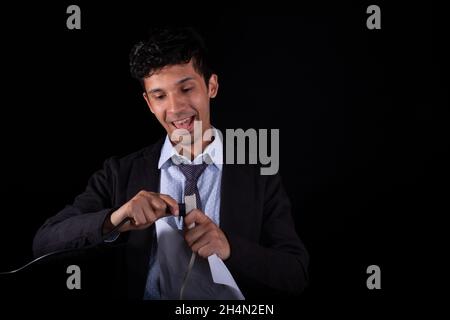 Heureux entrepreneur réussi à connecter un câble d'alimentation., isolé sur fond noir.Jeune adulte jeune homme en robe élégante.Latino-américain.Se connecter à Banque D'Images