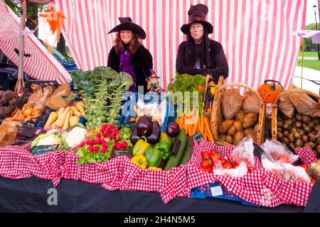 Deux porte-étals de femme sur un marché fermier au Rose Garden Wynyard Hall fermé pour Halloween servant des fruits et des légumes sous la pluie battante Banque D'Images