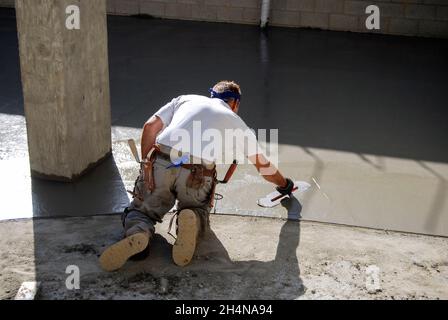 Béton Mason lissant une dalle fraîchement versée sur le sol Banque D'Images