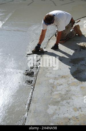 Béton Mason lissant une dalle fraîchement versée sur le sol Banque D'Images