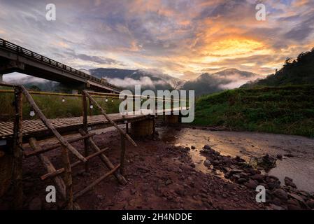 Magnifique paysage pittoresque du pont en bambou en bois avec le brouillard et le ciel spectaculaire en arrière-plan au coucher du soleil à Sapun dans la province de Nan, au nord du T Banque D'Images