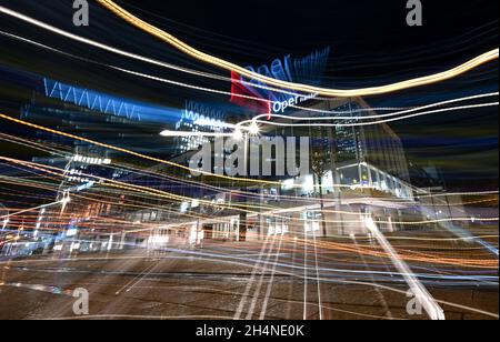 02 novembre 2021, Hessen, Francfort-sur-le-main : des traces de lumière provenant des tramways et des bicyclettes qui passent ainsi que les lumières des feux de rue peuvent être vues dans la soirée devant l'Opéra (r) et le Schauspiel (tourné avec exposition longue, zoom et effet de balayage).La ville de Francfort-sur-le-main présentera une étude approfondie du double complexe devant être rénové le 4 novembre 2021.Photo: Arne Dedert/dpa Banque D'Images