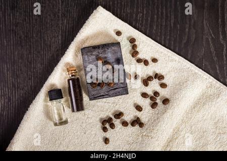 Spa marron : savon naturel, huile aromatique, grains de café et serviette sur fond de bois. Banque D'Images
