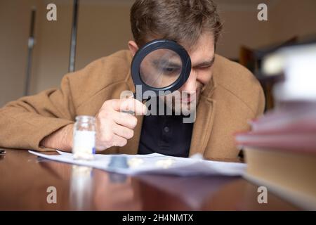 un détective recherche des indices avec une loupe dans la salle. Banque D'Images
