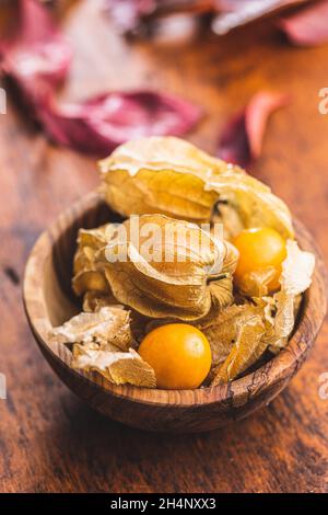 Physalis peruviana.Le cape de la groseille ou des cerises moulées fruits dans un bol sur une table en bois. Banque D'Images