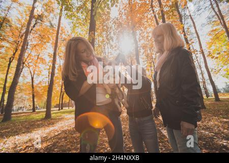 Mère, grand-mère et fille tient Jack russell terrier et joue avec lui en automne dehors.Concept d'animal de compagnie et de famille Banque D'Images